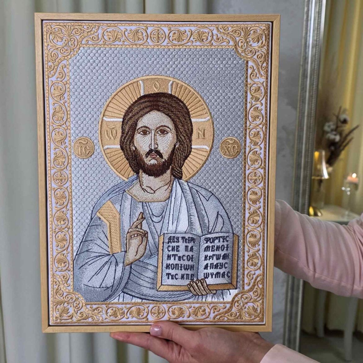 Ікона Спасителя, вишита шовком, з розкритим Євангелієм і грецьким написом, у дерев'яній рамці в руках