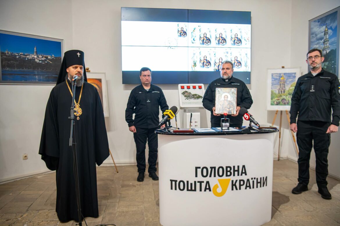 Архієпископ у чорному клобуку з панагією говорить у мікрофон; поруч священник у темній формі тримає ікону Архангела, двоє представників ГУР у темній формі, стійка «Головна пошта України», на екрані — аркуш марок із зображенням Архангела
